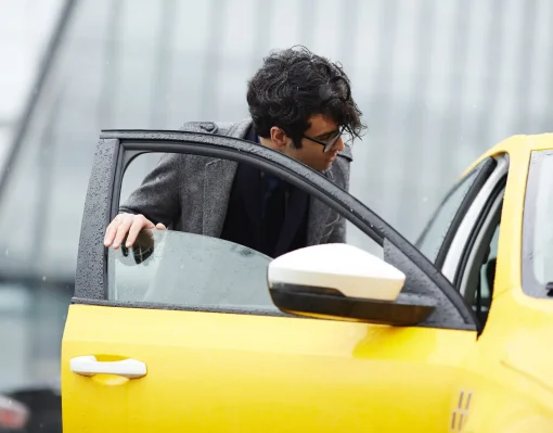 Portrait of hurrying businessman catching taxi and opening car door on rainy autumn street